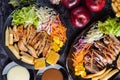 Sliced Ã¢â¬â¹Ã¢â¬â¹pork and Ã¢â¬â¹Ã¢â¬â¹chicken steak with bread, carrots, cauliflower, lettuce and corn on a black plate on a cement floor Royalty Free Stock Photo